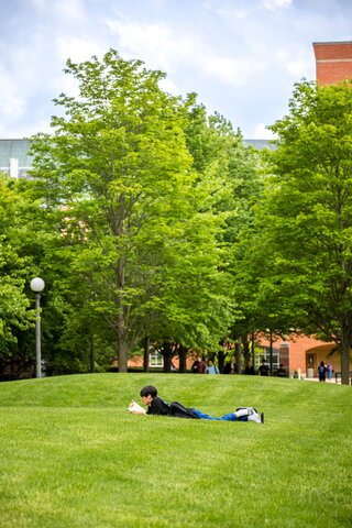 Student reading a book on the North Engineering Quad.