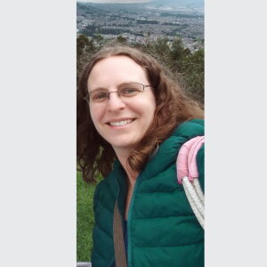 Alana Ackerman, Anthropology Graduate Student. A woman in a green jacket smiling.
